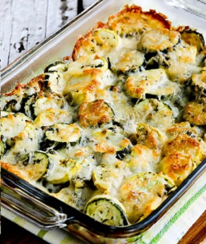 A variety of zucchini dishes including zucchini fritters, zucchini bread, and stuffed zucchini boats on a rustic wooden table.