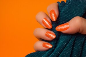 Trendy summer nails with a range of orange shades including neon, burnt, and glitter finishes, ideal for seasonal flair.