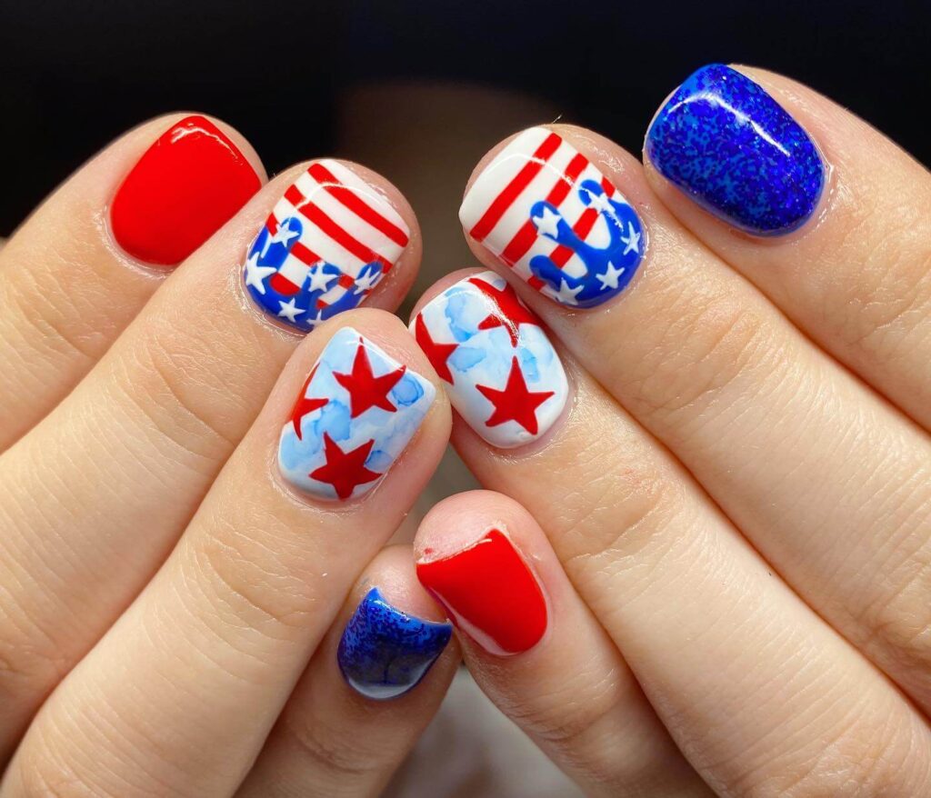 Colorful 4th of July nails featuring stars, stripes, and glitter in red, white, and blue.