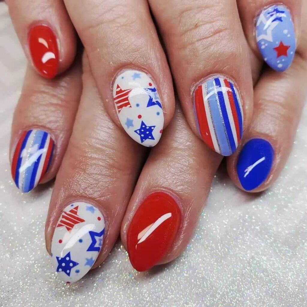 Colorful 4th of July nails featuring stars, stripes, and glitter in red, white, and blue.