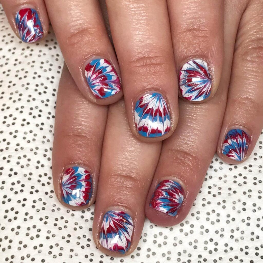 Colorful 4th of July nails featuring stars, stripes, and glitter in red, white, and blue.