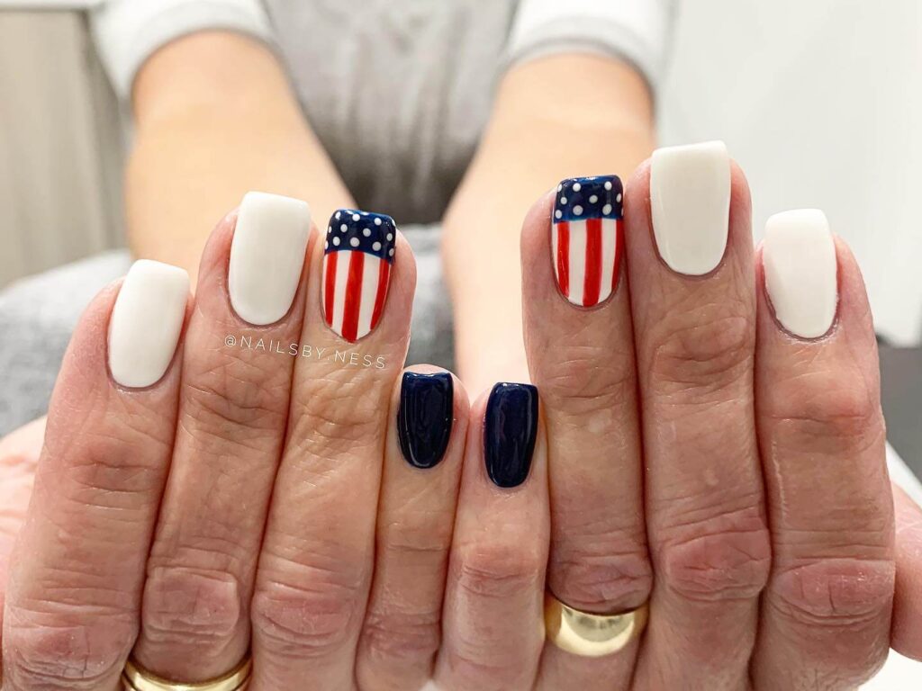 Colorful 4th of July nails featuring stars, stripes, and glitter in red, white, and blue.