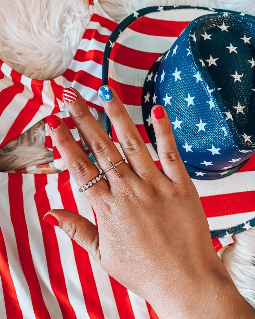 Colorful 4th of July nails featuring stars, stripes, and glitter in red, white, and blue.