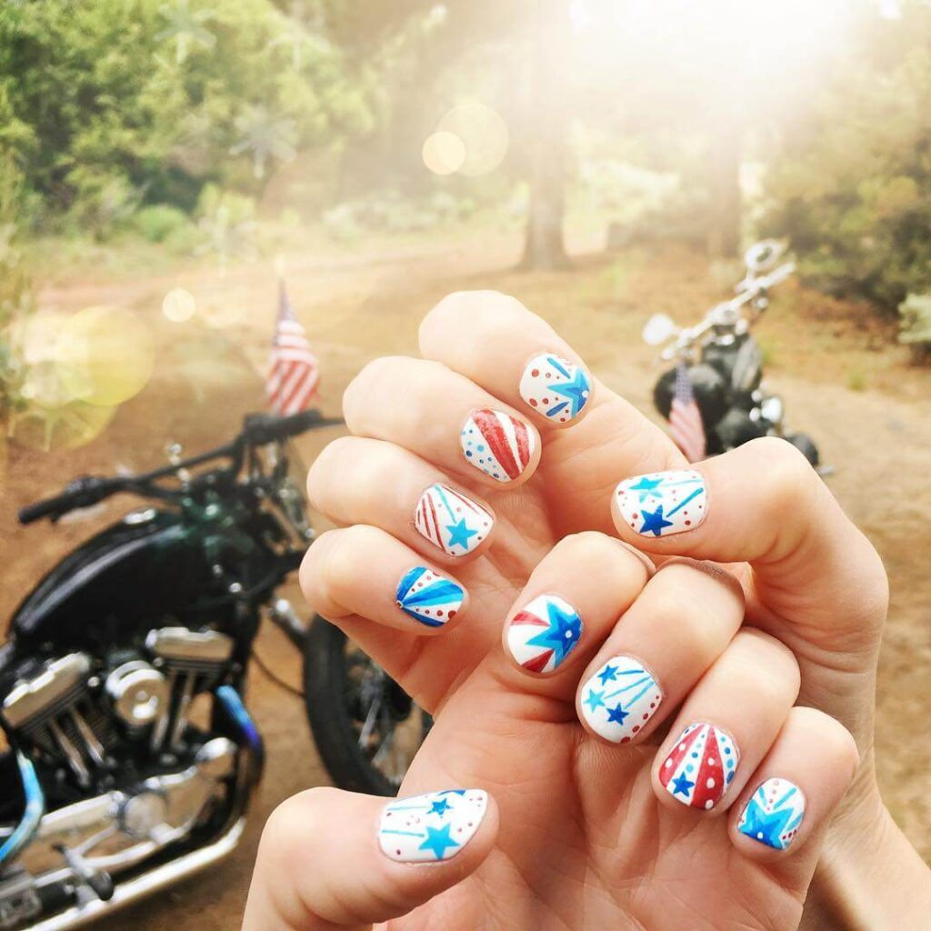 Colorful 4th of July nails featuring stars, stripes, and glitter in red, white, and blue.