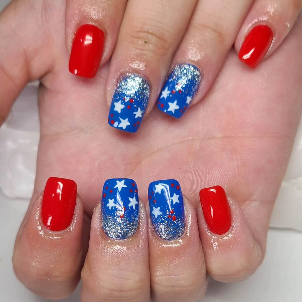 Colorful 4th of July nails featuring stars, stripes, and glitter in red, white, and blue.