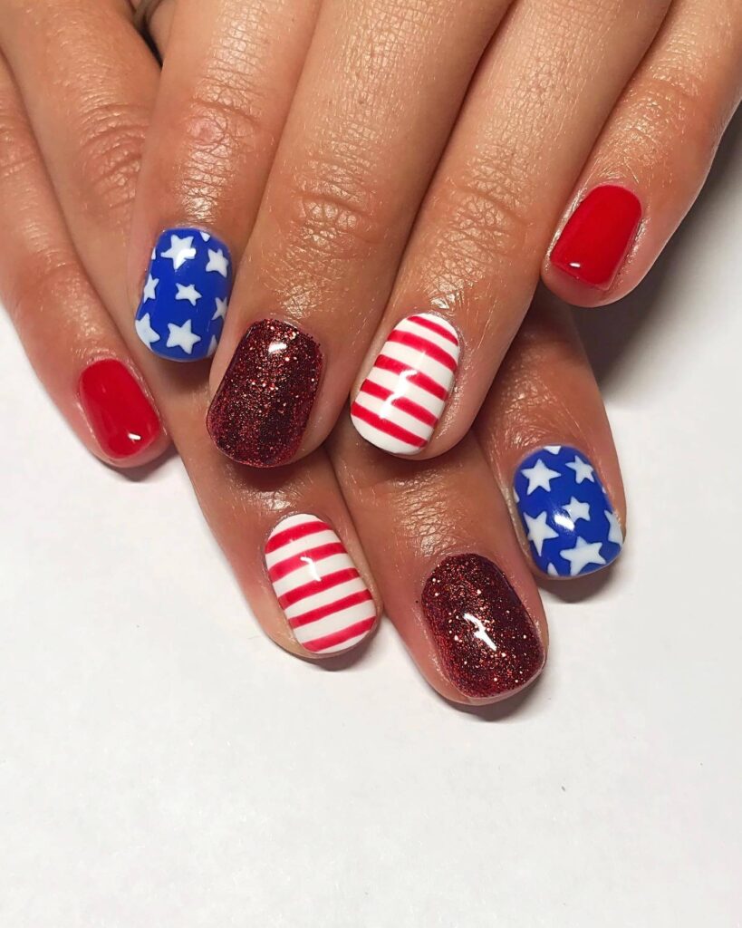 Colorful 4th of July nails featuring stars, stripes, and glitter in red, white, and blue.