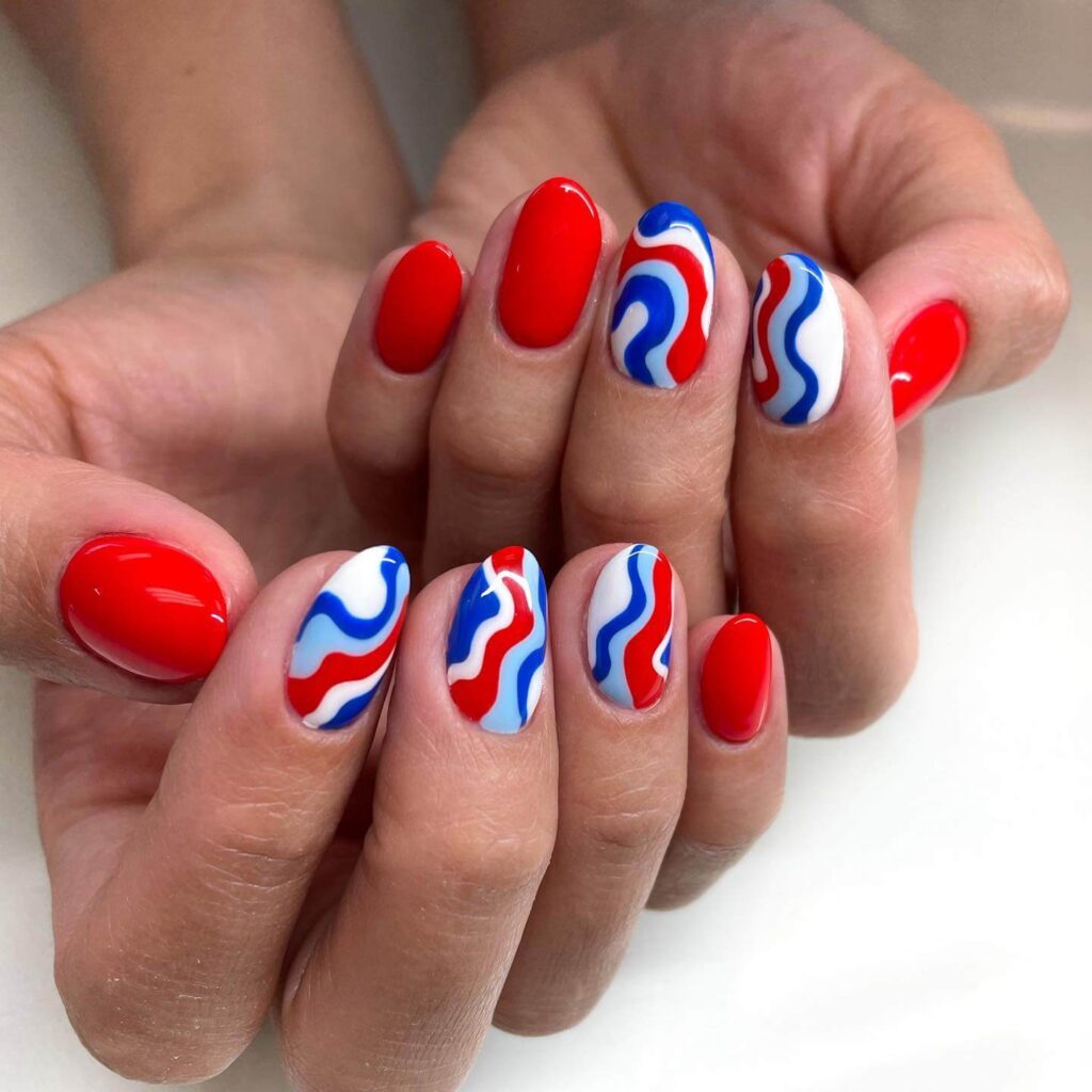 Colorful 4th of July nails featuring stars, stripes, and glitter in red, white, and blue.