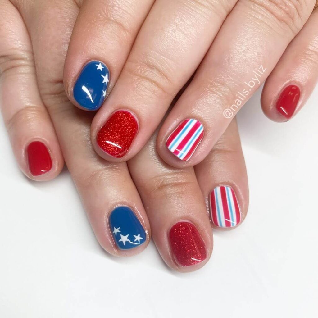 Colorful 4th of July nails featuring stars, stripes, and glitter in red, white, and blue.