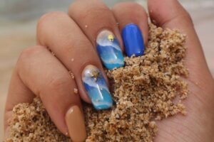 A collection of beach-themed nail designs featuring ocean blues, sandy taupe, and sunset gradients, perfect for summer vacations.