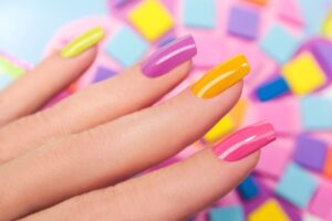 Bright and playful summer nail art with vibrant shades of blue, pink, and yellow, featuring beach-inspired designs and floral patterns.