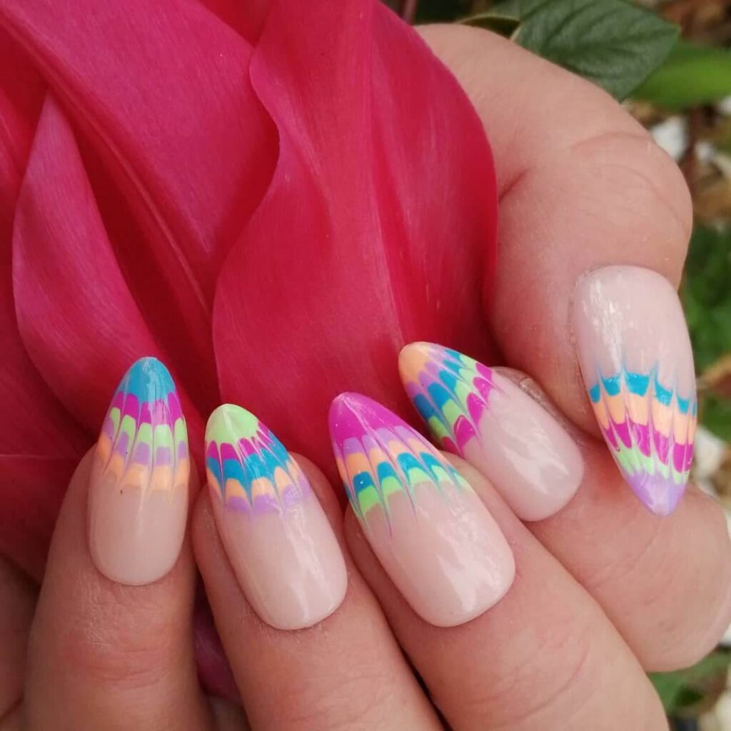 Bright and playful summer nail art with vibrant shades of blue, pink, and yellow, featuring beach-inspired designs and floral patterns.