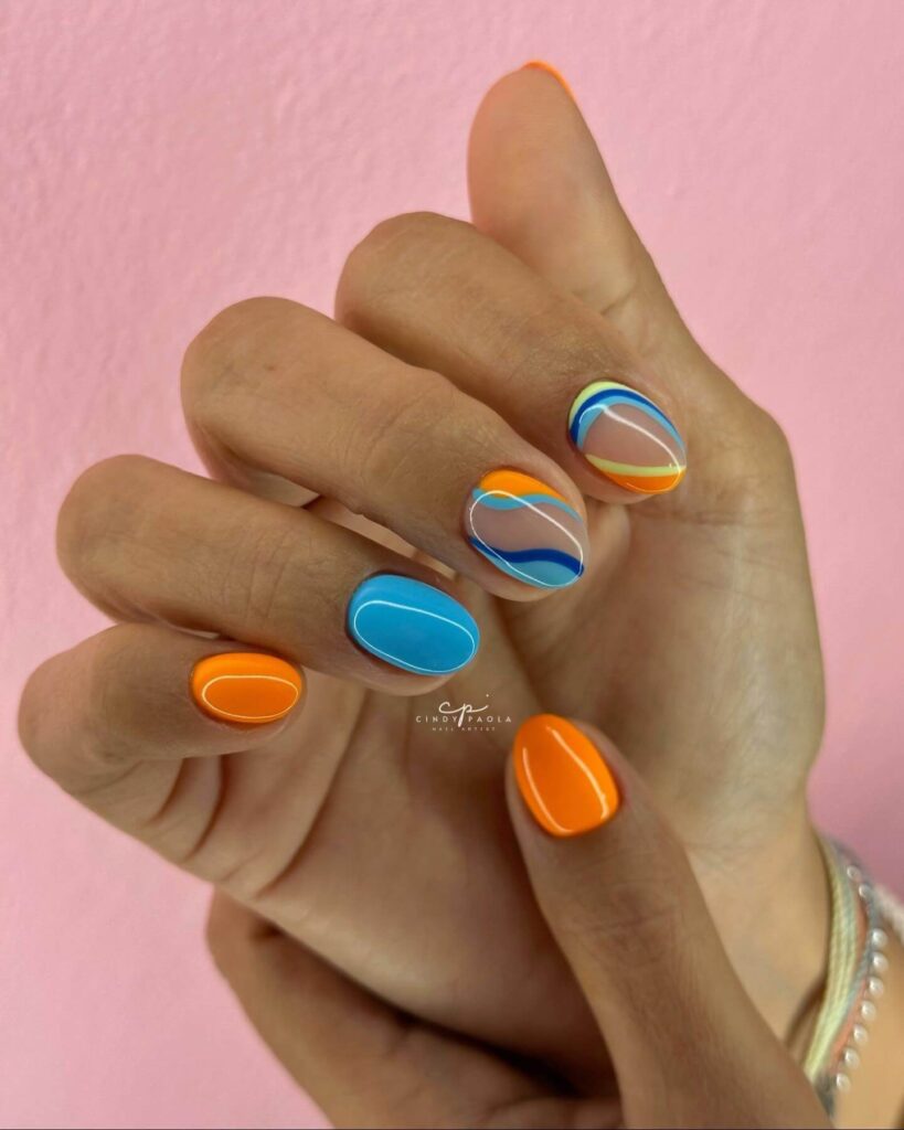 Bright and playful summer nail art with vibrant shades of blue, pink, and yellow, featuring beach-inspired designs and floral patterns.