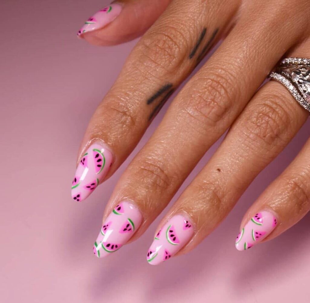 Bright watermelon nails featuring vibrant summer pink and green polish, accented with playful black seeds, perfect for a fresh summer look.