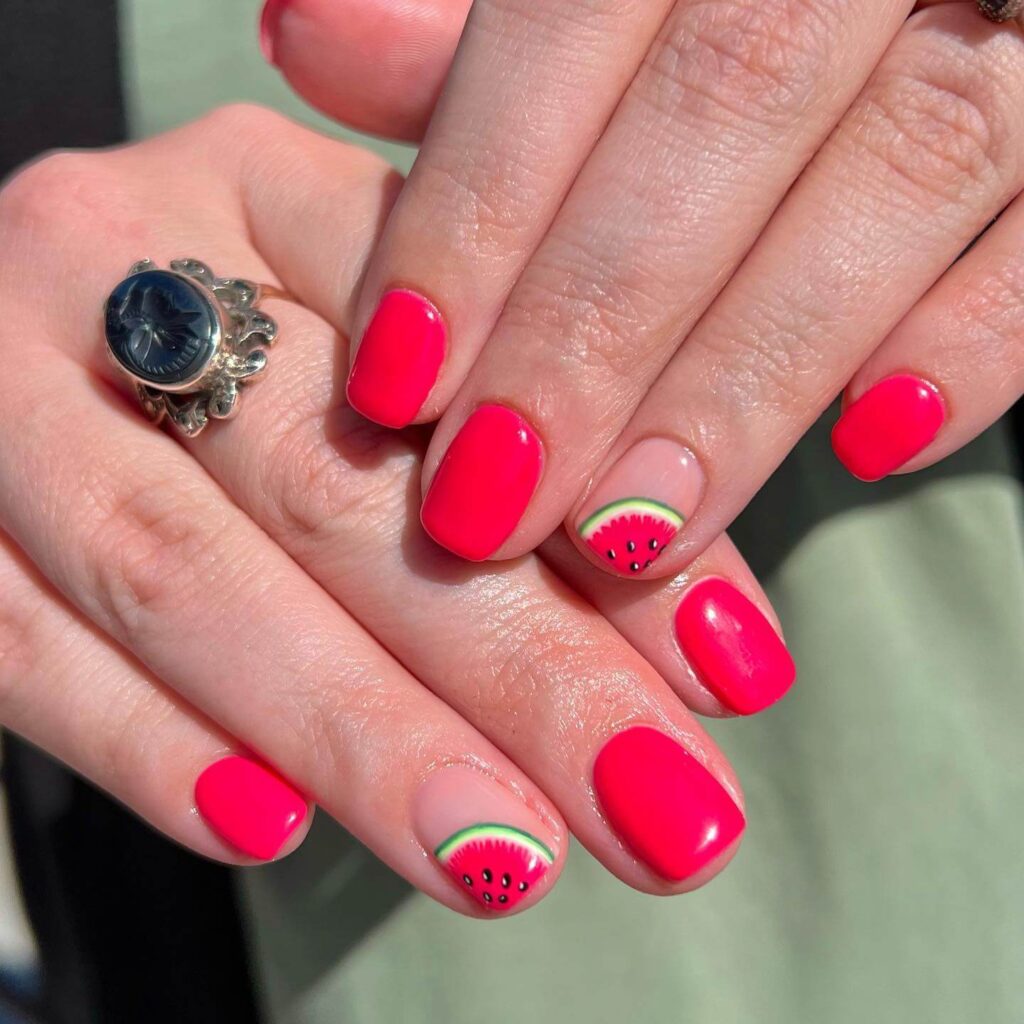 Bright watermelon nails featuring vibrant summer pink and green polish, accented with playful black seeds, perfect for a fresh summer look.