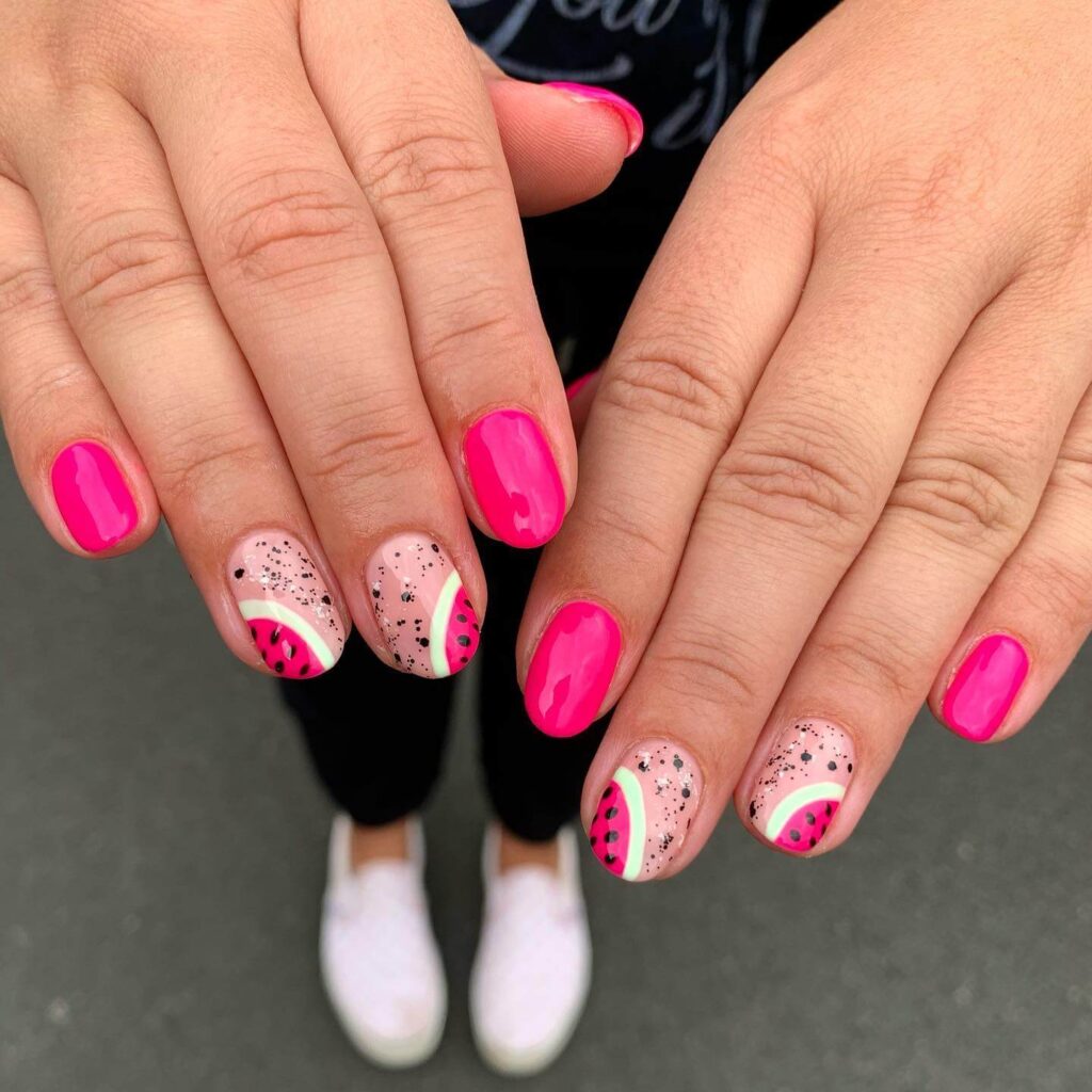 Bright watermelon nails featuring vibrant summer pink and green polish, accented with playful black seeds, perfect for a fresh summer look.