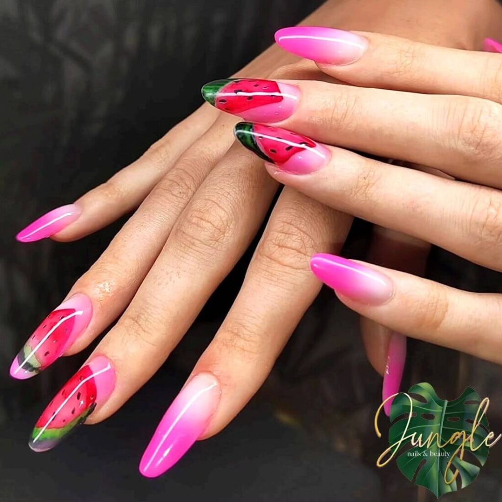 Bright watermelon nails featuring vibrant summer pink and green polish, accented with playful black seeds, perfect for a fresh summer look.