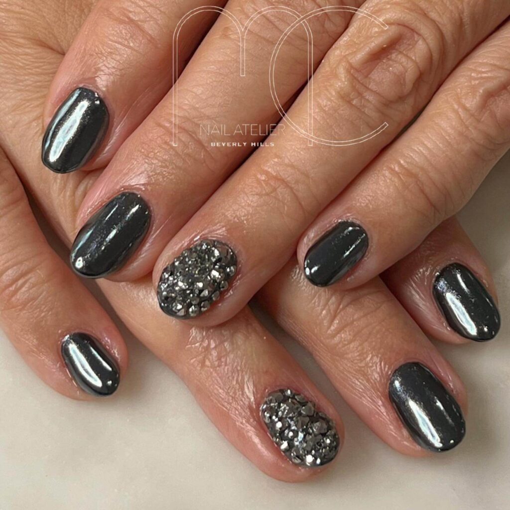 Close-up of hands showcasing various metallic nails designs, including black nails with silver flakes, dark gold nail polish, and metallic red acrylic nails.