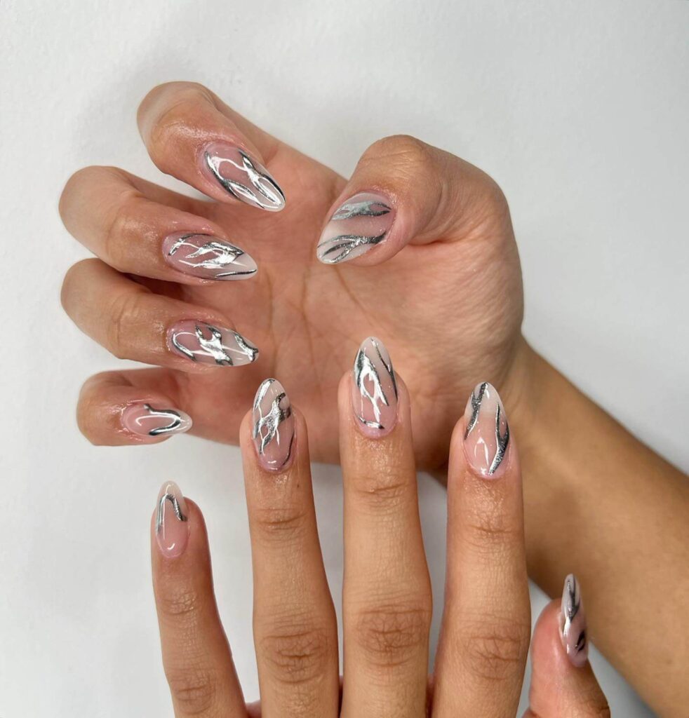 Close-up of hands showcasing various metallic nails designs, including black nails with silver flakes, dark gold nail polish, and metallic red acrylic nails.