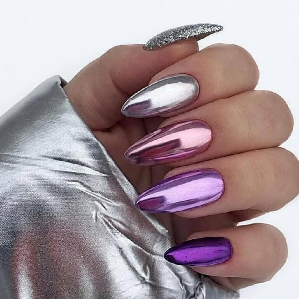 Close-up of hands showcasing various metallic nails designs, including black nails with silver flakes, dark gold nail polish, and metallic red acrylic nails.