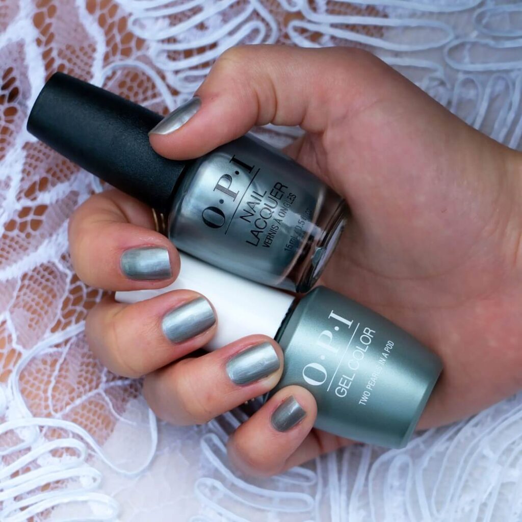 Close-up of hands showcasing various metallic nails designs, including black nails with silver flakes, dark gold nail polish, and metallic red acrylic nails.