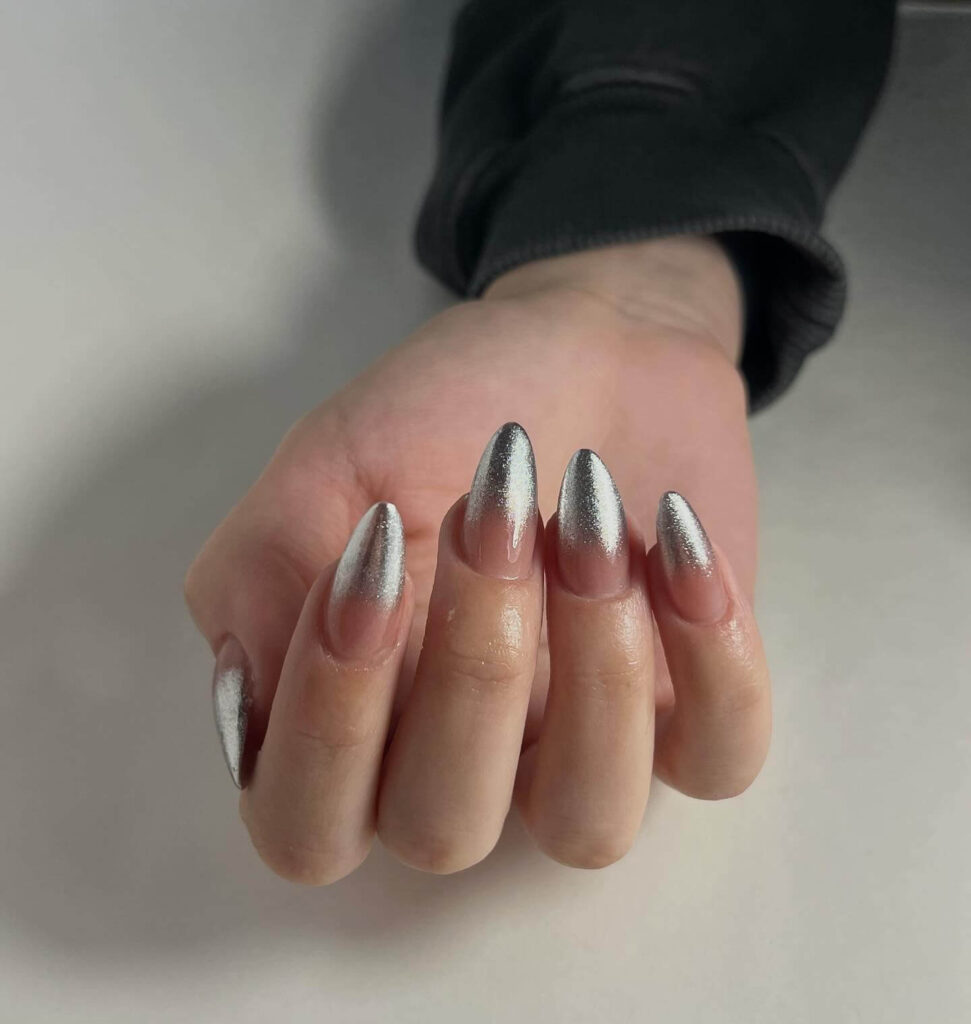 Close-up of hands showcasing various metallic nails designs, including black nails with silver flakes, dark gold nail polish, and metallic red acrylic nails.