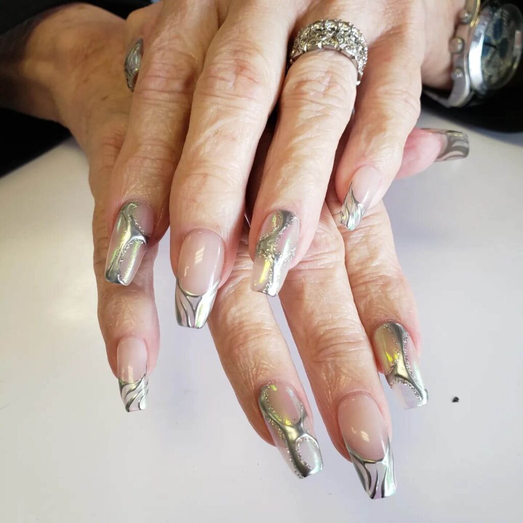 Close-up of hands showcasing various metallic nails designs, including black nails with silver flakes, dark gold nail polish, and metallic red acrylic nails.