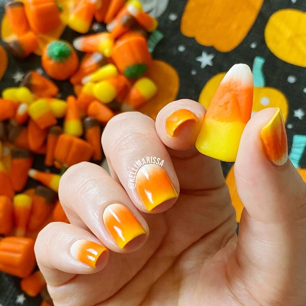 Festive candy corn nails with vibrant Halloween colors and cute designs like pumpkins and scarecrows.