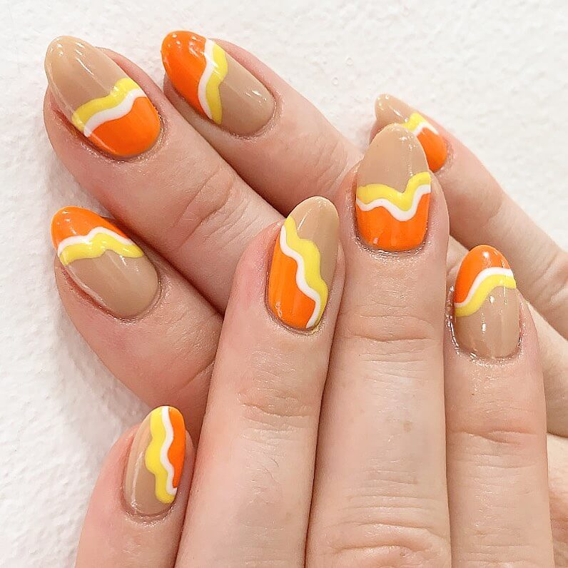 Festive candy corn nails with vibrant Halloween colors and cute designs like pumpkins and scarecrows.