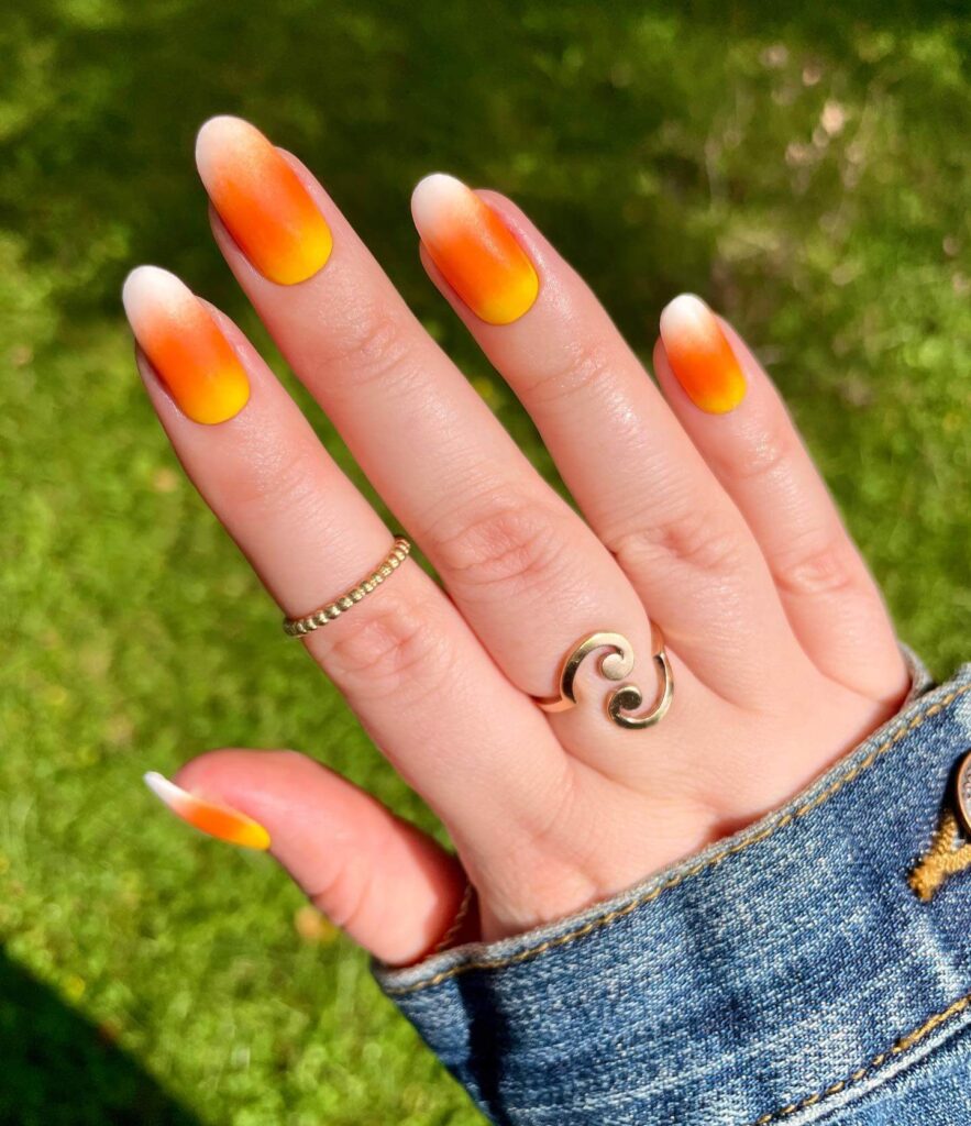 Festive candy corn nails with vibrant Halloween colors and cute designs like pumpkins and scarecrows.