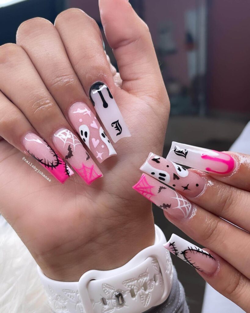 A set of Halloween acrylic nails with spooky nail designs, including black and red accents, ghosts, and candy corn-themed nails.