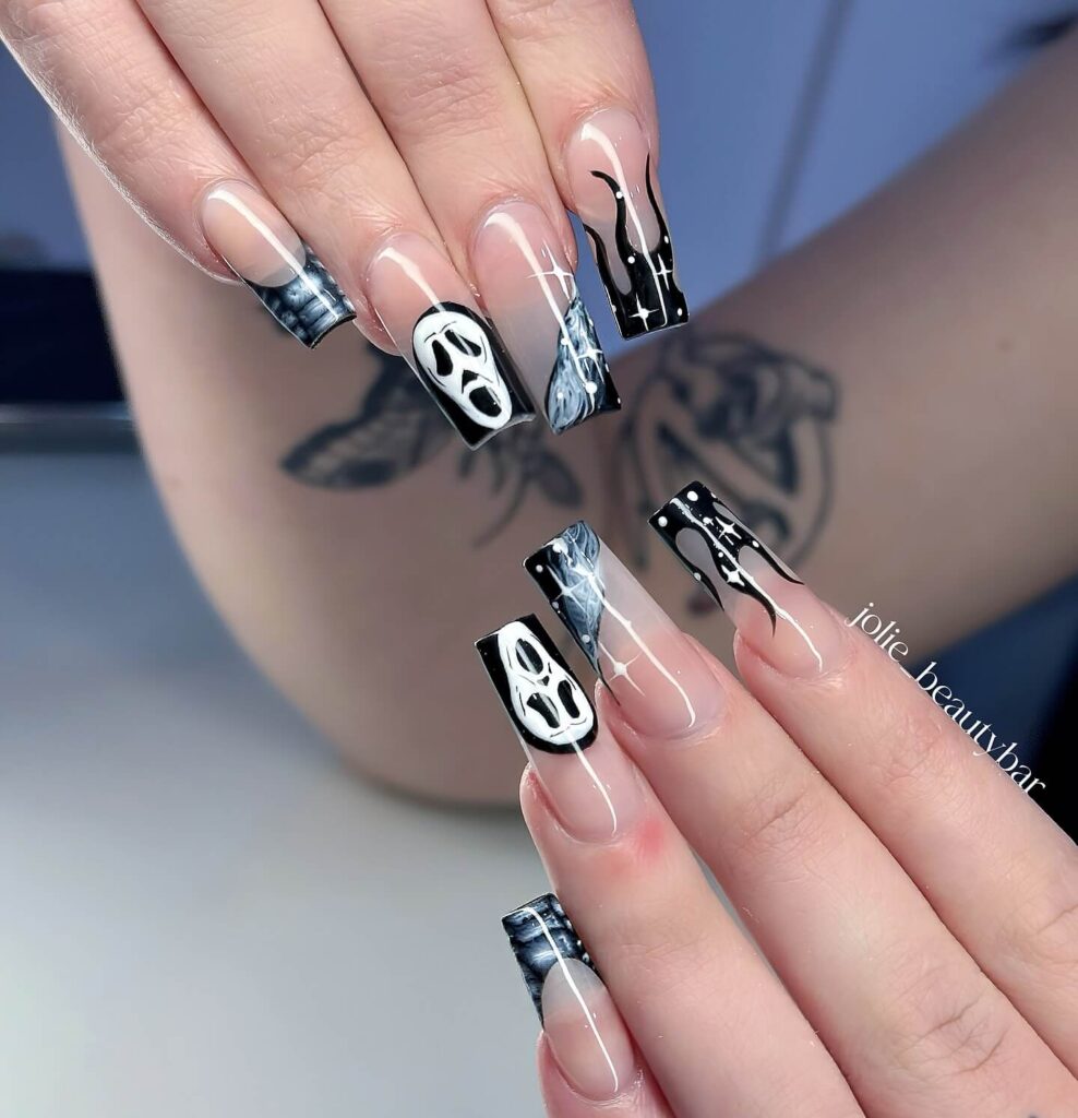 A set of Halloween acrylic nails with spooky nail designs, including black and red accents, ghosts, and candy corn-themed nails.