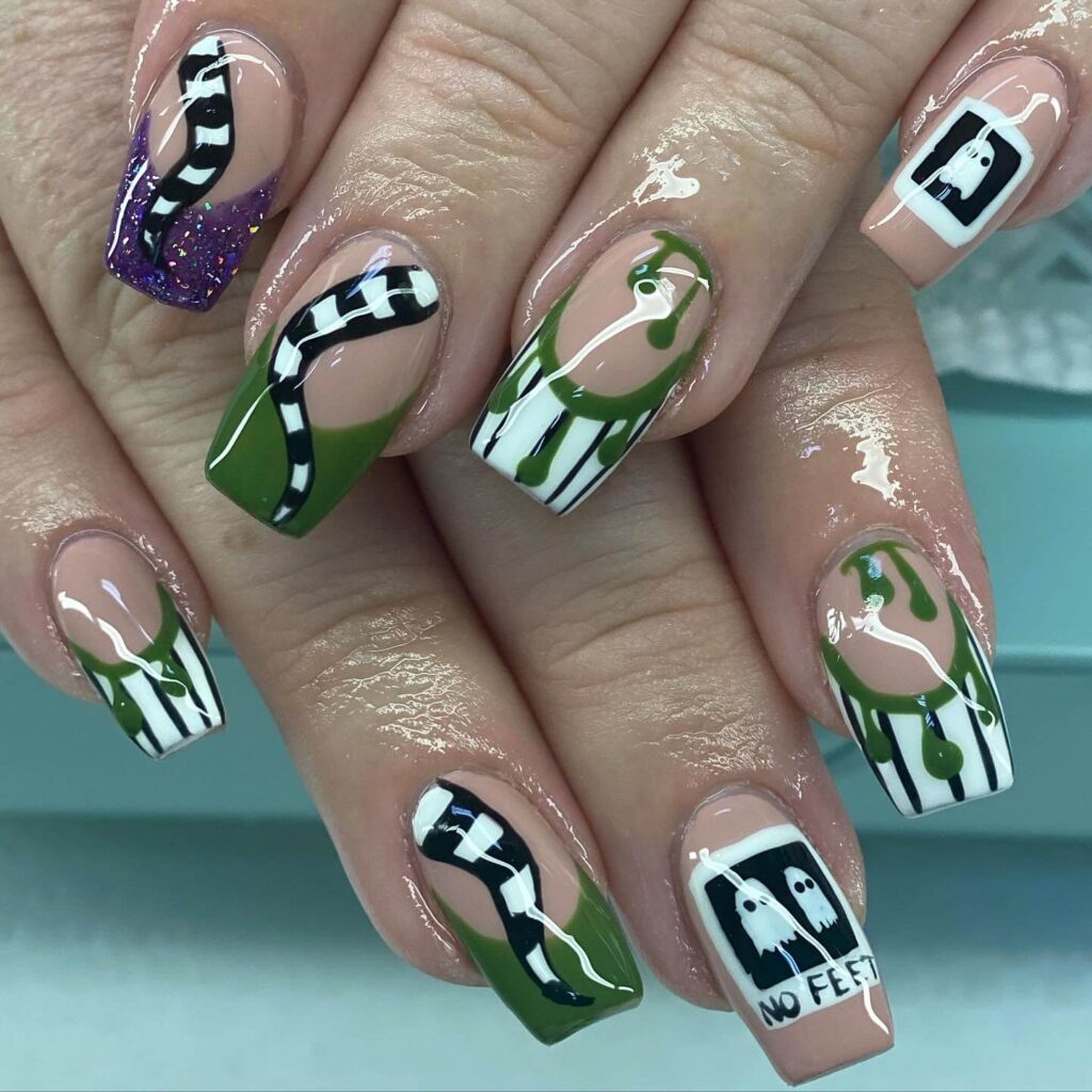 A set of Halloween acrylic nails with spooky nail designs, including black and red accents, ghosts, and candy corn-themed nails.