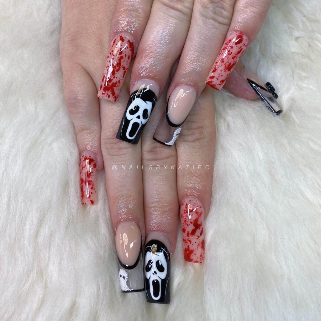 A set of Halloween acrylic nails with spooky nail designs, including black and red accents, ghosts, and candy corn-themed nails.