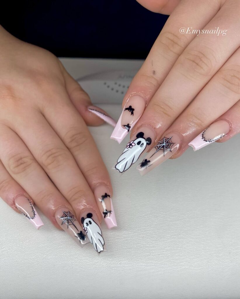 A set of Halloween acrylic nails with spooky nail designs, including black and red accents, ghosts, and candy corn-themed nails.