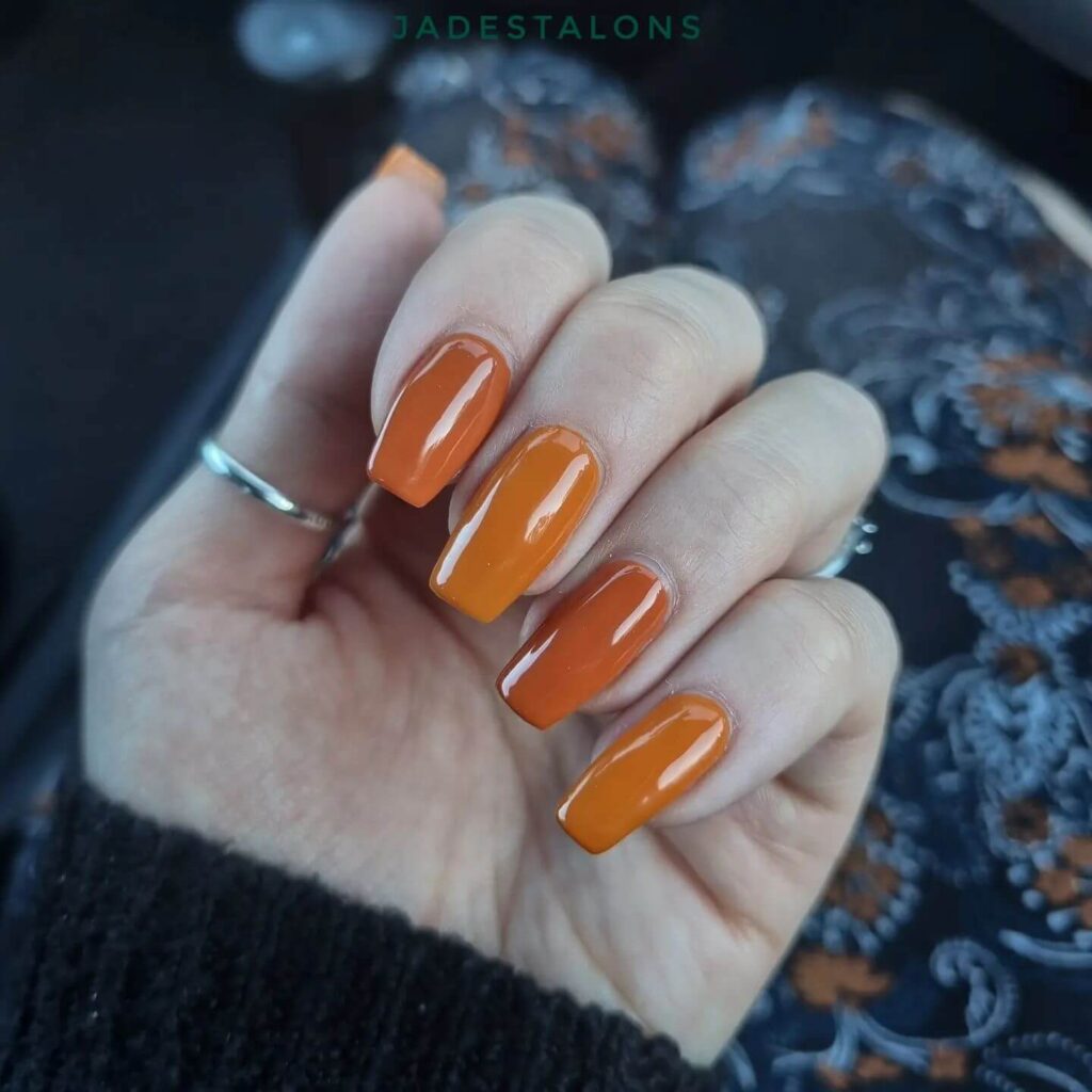 Close-up of warm-toned pumpkin spice nails with a fall-inspired design.