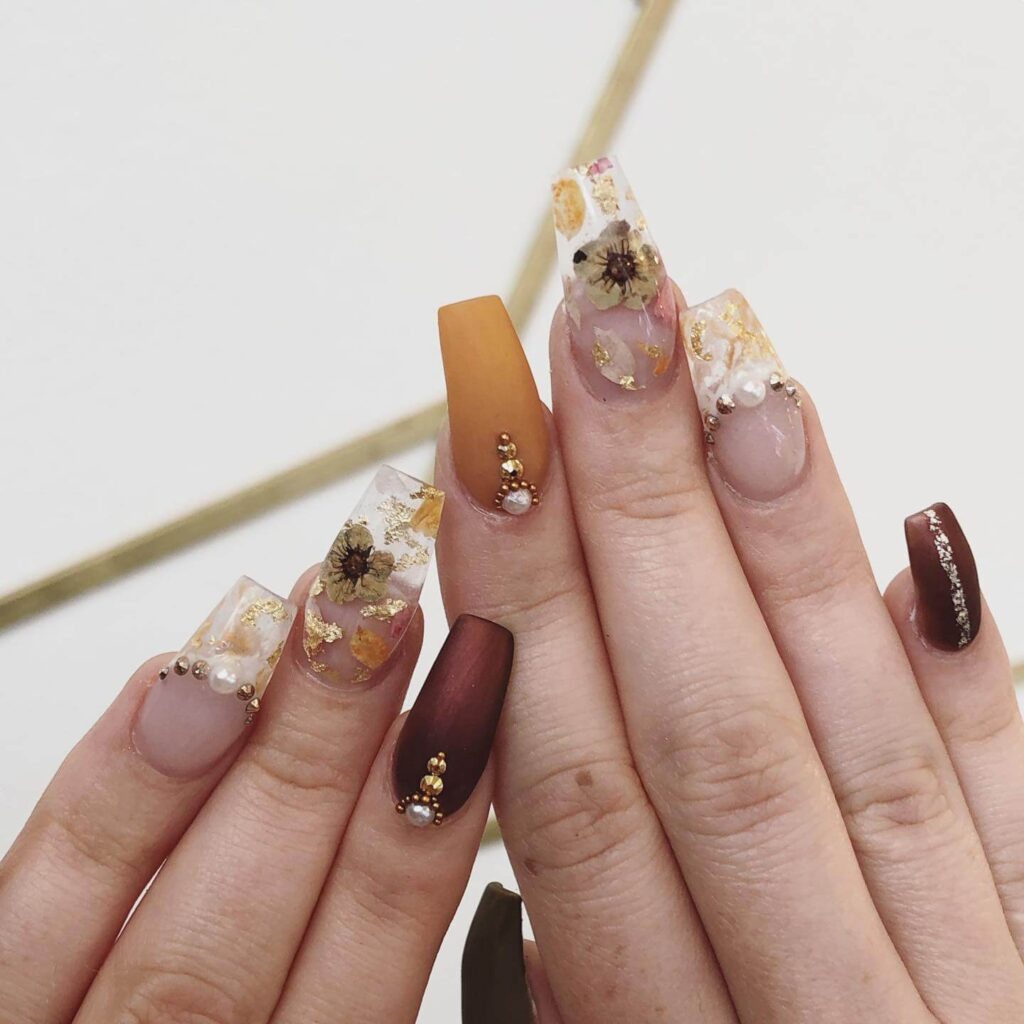 Close-up of warm-toned pumpkin spice nails with a fall-inspired design.