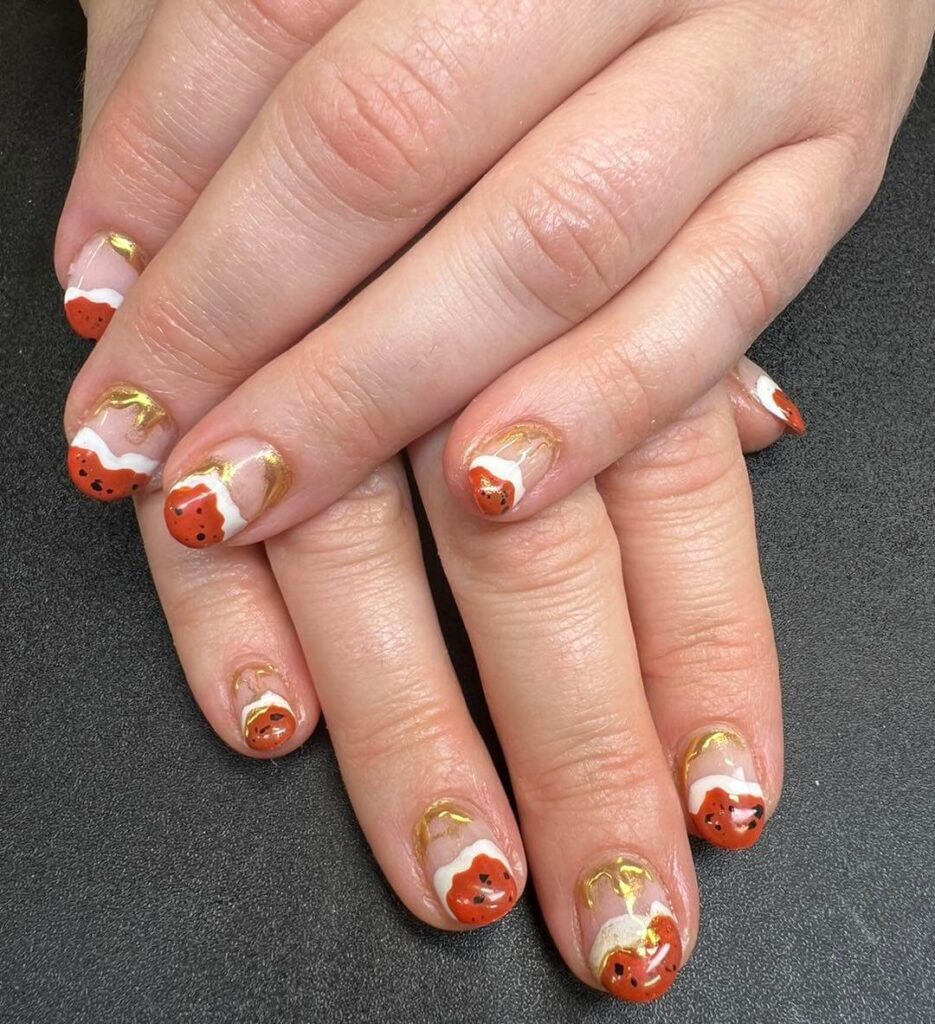 Close-up of warm-toned pumpkin spice nails with a fall-inspired design.