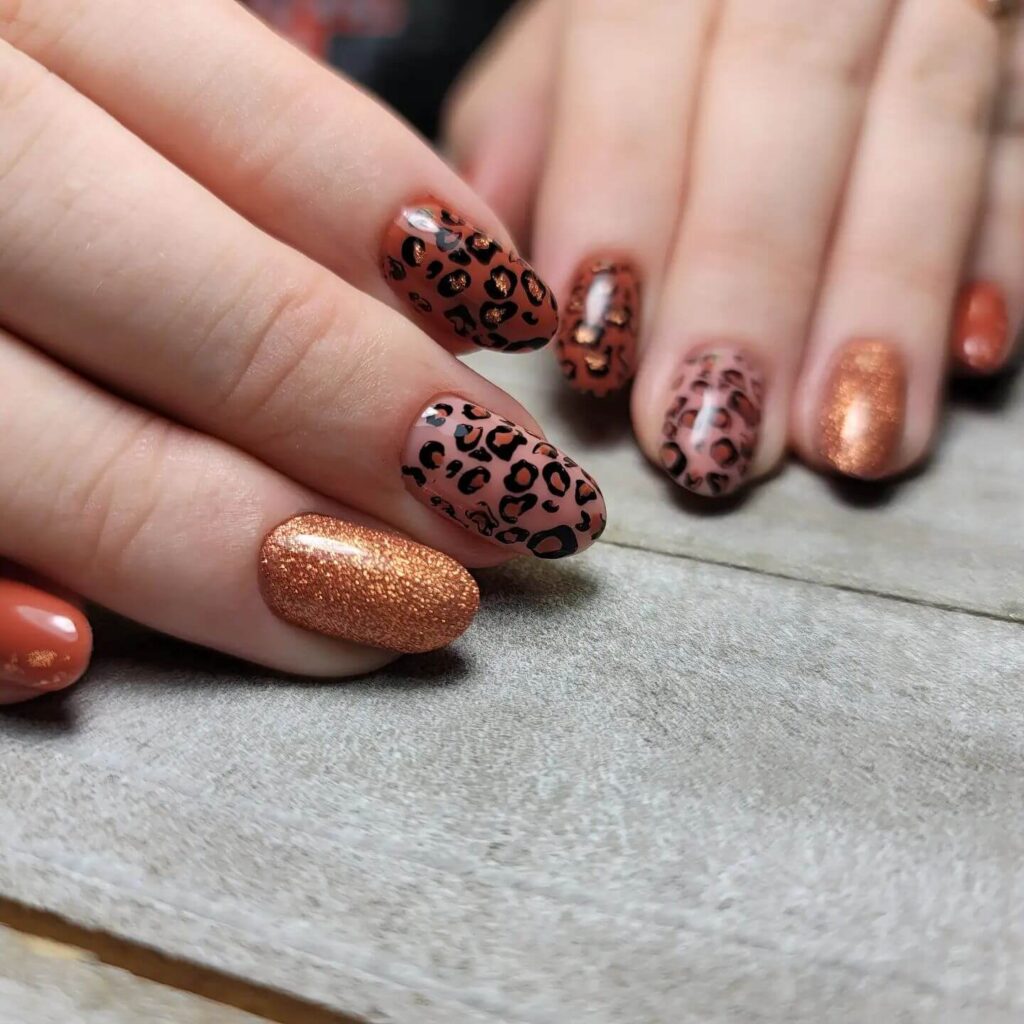 Close-up of warm-toned pumpkin spice nails with a fall-inspired design.