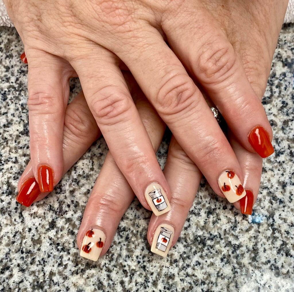 Close-up of warm-toned pumpkin spice nails with a fall-inspired design.