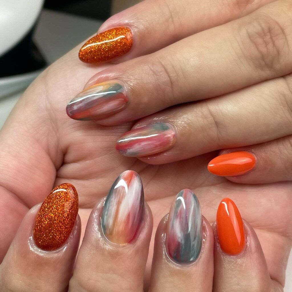 Close-up of warm-toned pumpkin spice nails with a fall-inspired design.