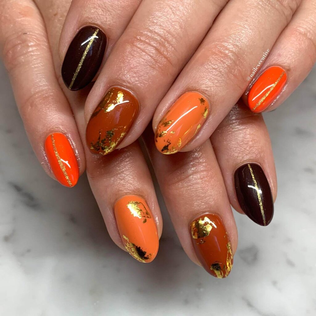 Close-up of warm-toned pumpkin spice nails with a fall-inspired design.