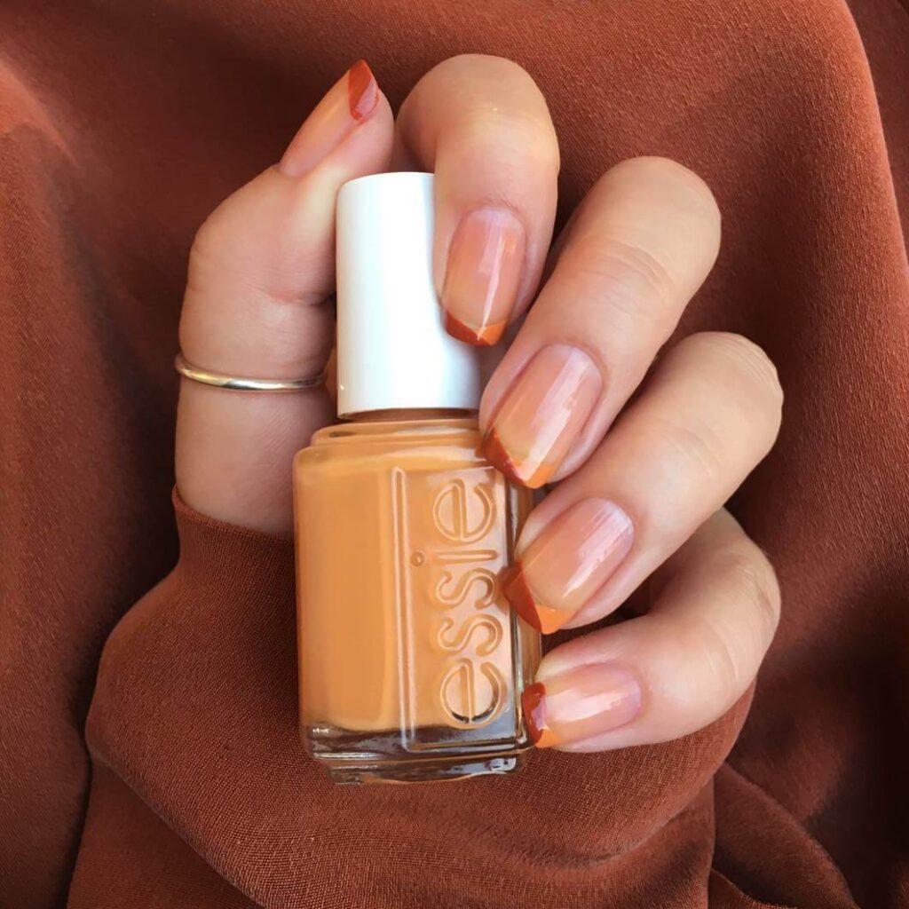 Close-up of warm-toned pumpkin spice nails with a fall-inspired design.