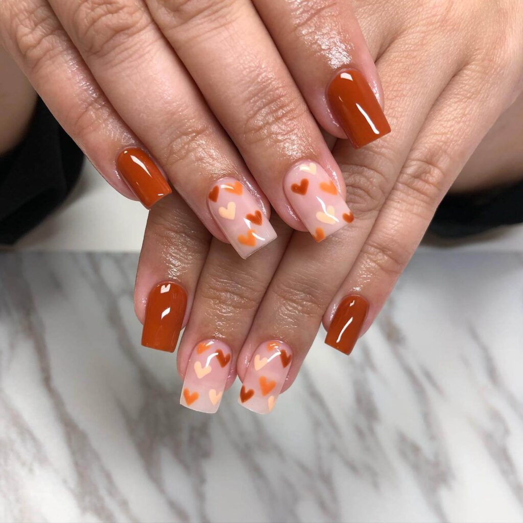 Close-up of warm-toned pumpkin spice nails with a fall-inspired design.