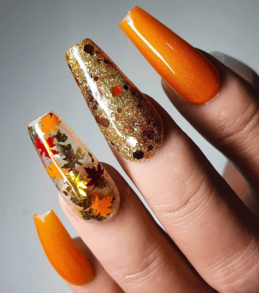 Close-up of warm-toned pumpkin spice nails with a fall-inspired design.