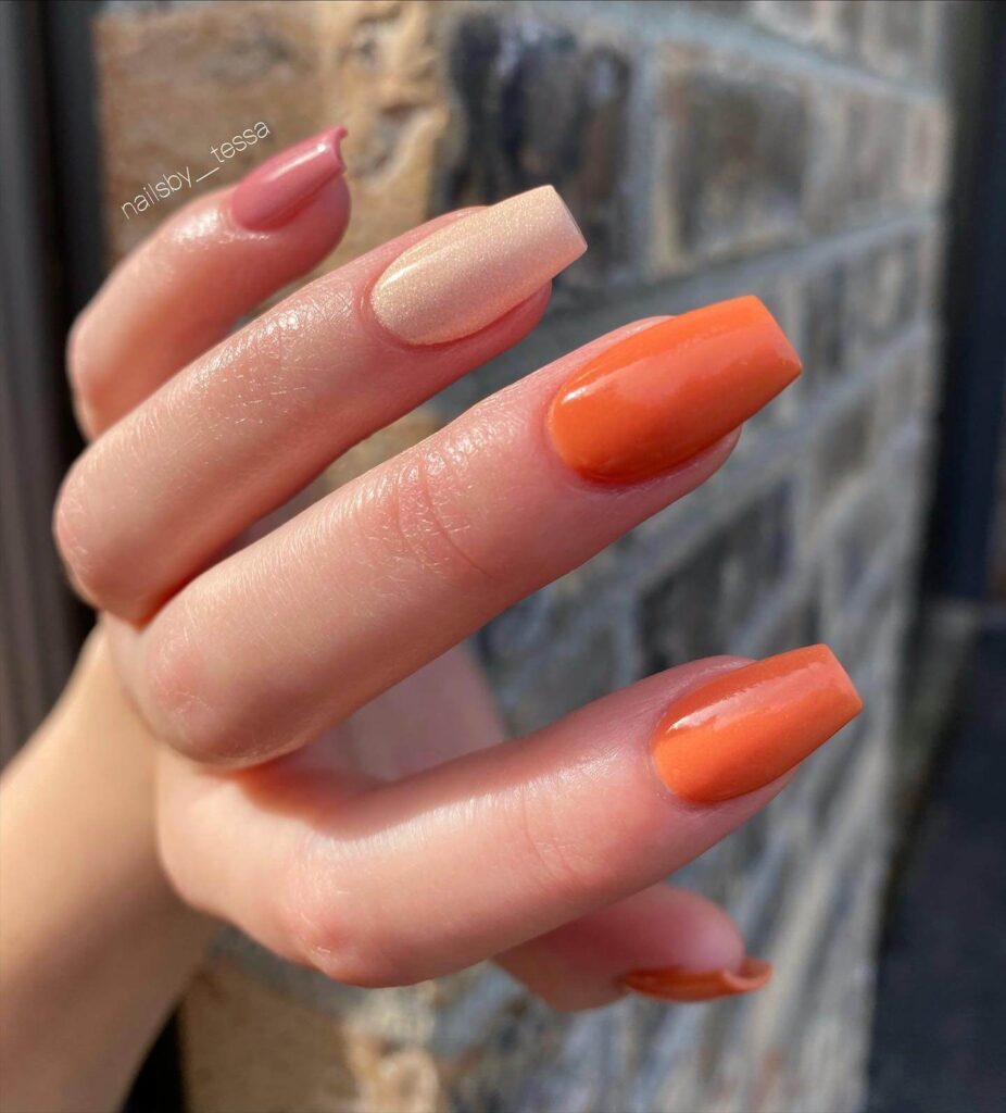 Close-up of warm-toned pumpkin spice nails with a fall-inspired design.