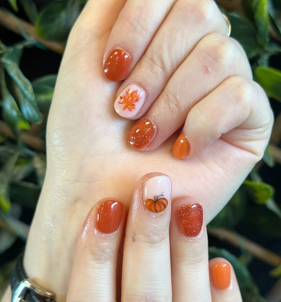 Close-up of warm-toned pumpkin spice nails with a fall-inspired design.