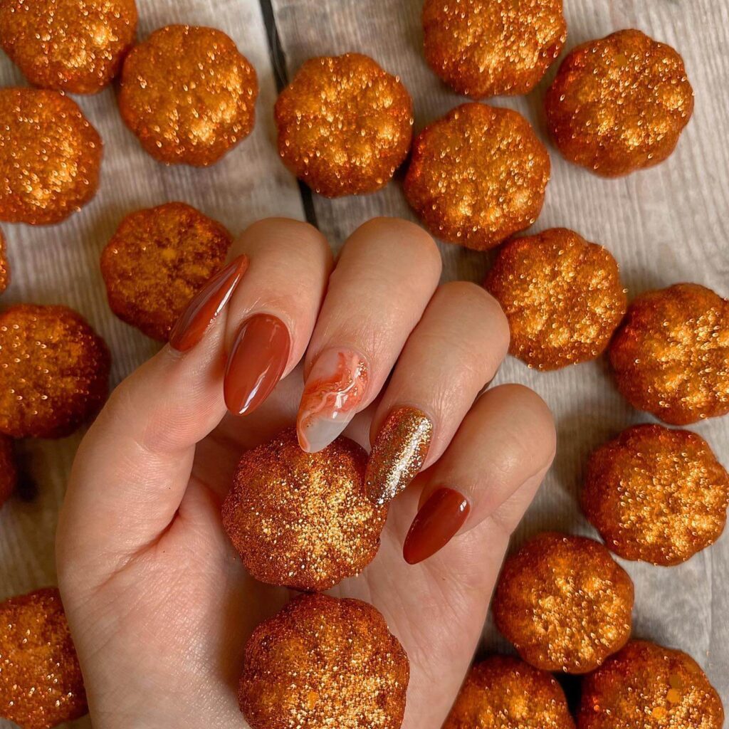 Close-up of warm-toned pumpkin spice nails with a fall-inspired design.