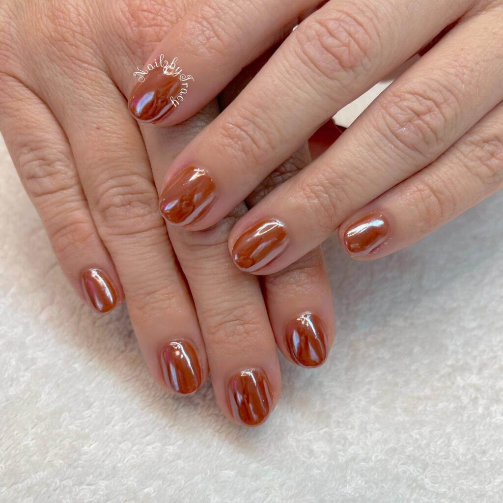 Close-up of warm-toned pumpkin spice nails with a fall-inspired design.