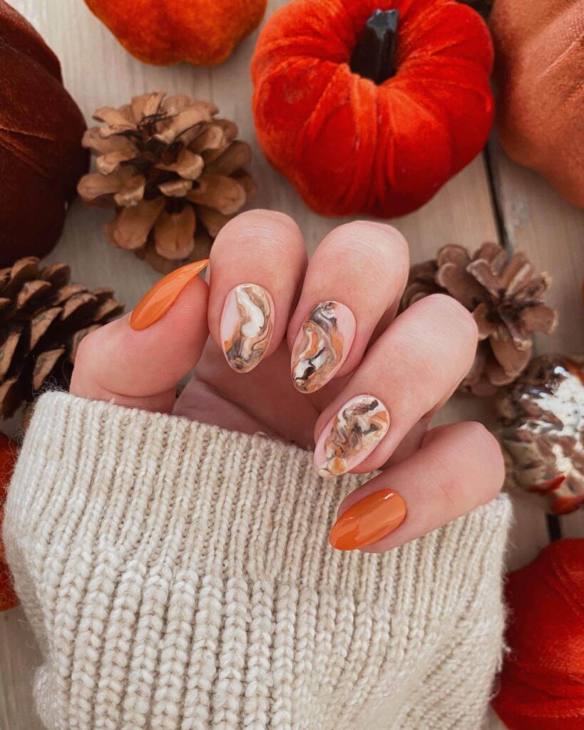 Close-up of warm-toned pumpkin spice nails with a fall-inspired design.