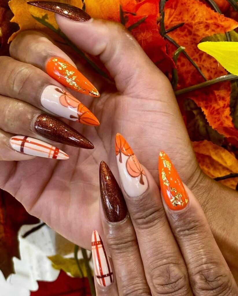 Close-up of warm-toned pumpkin spice nails with a fall-inspired design.